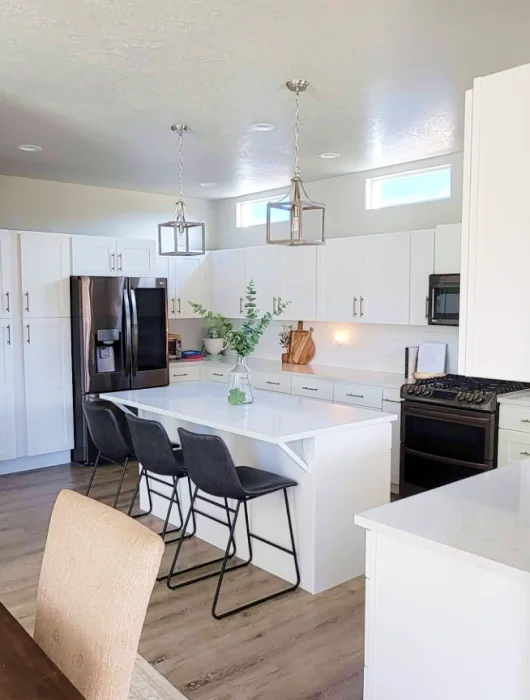 white cabinets, a white counter top, and has black barstool chairs